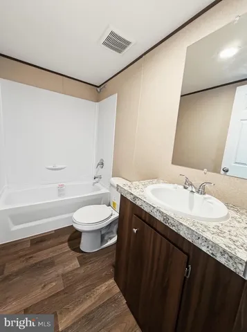a bathroom with a granite countertop sink toilet a large mirror and a bathtub