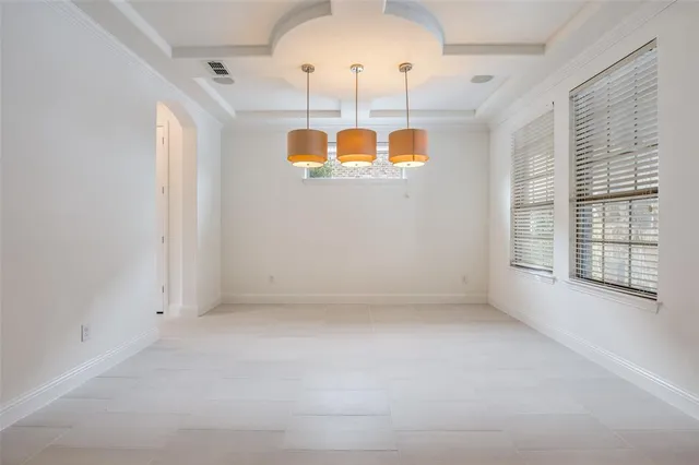 an empty room with a chandelier fan and windows