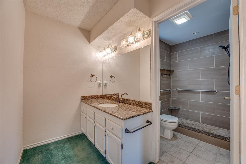 3410 Conlin Drive Rowlett, TX 75088 - Photo 20 of 27 a bathroom with a granite countertop sink a toilet a mirror and shower