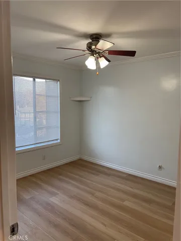an empty room with wooden floor fan and windows