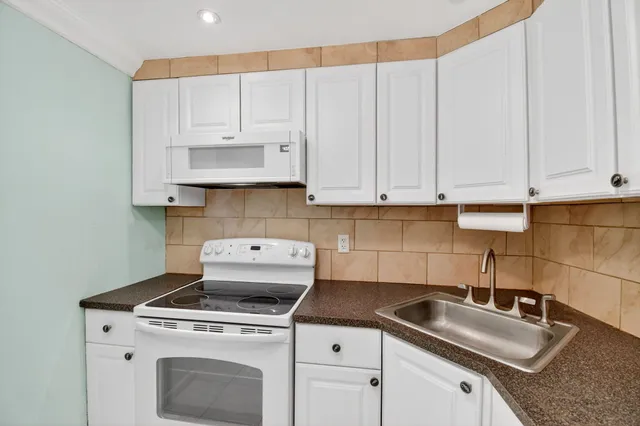a kitchen with granite countertop a sink a stove and cabinets