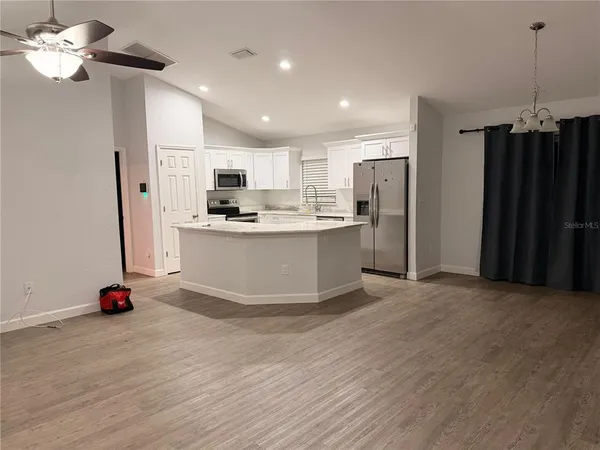 a view of kitchen with stainless steel appliances granite countertop a sink dishwasher a refrigerator and a dining table with wooden floor