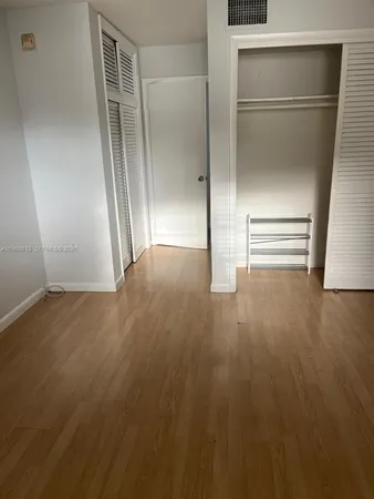 an empty room with wooden floor & cabinet