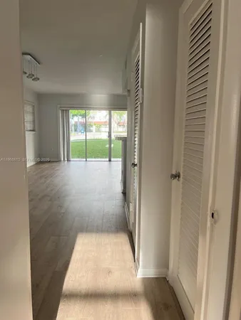 a view of a hallway with wooden floor and a living room