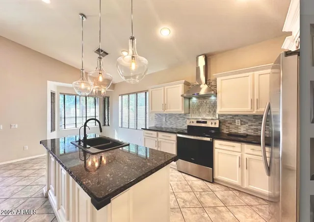 a kitchen with kitchen island granite countertop a stove a sink and chandelier