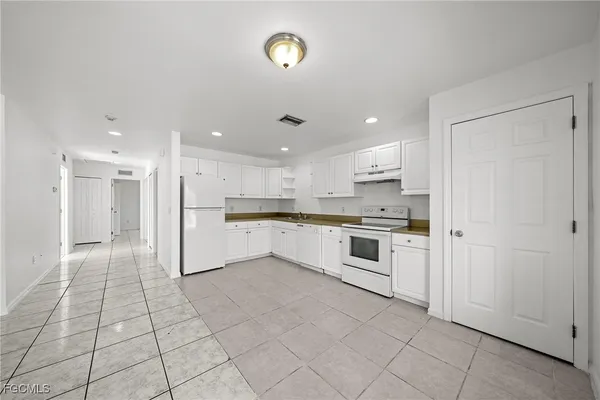 a large white kitchen with a stove a sink dishwasher and a refrigerator with white cabinets