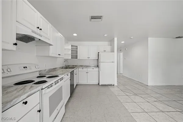a kitchen with white cabinets and appliances