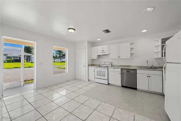 a large white kitchen with a sink and cabinets