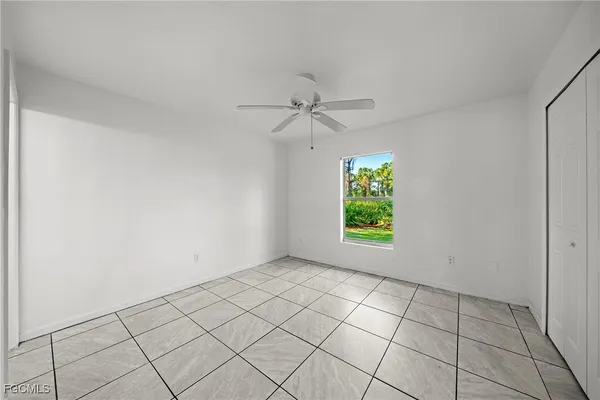 an empty room with windows and fan