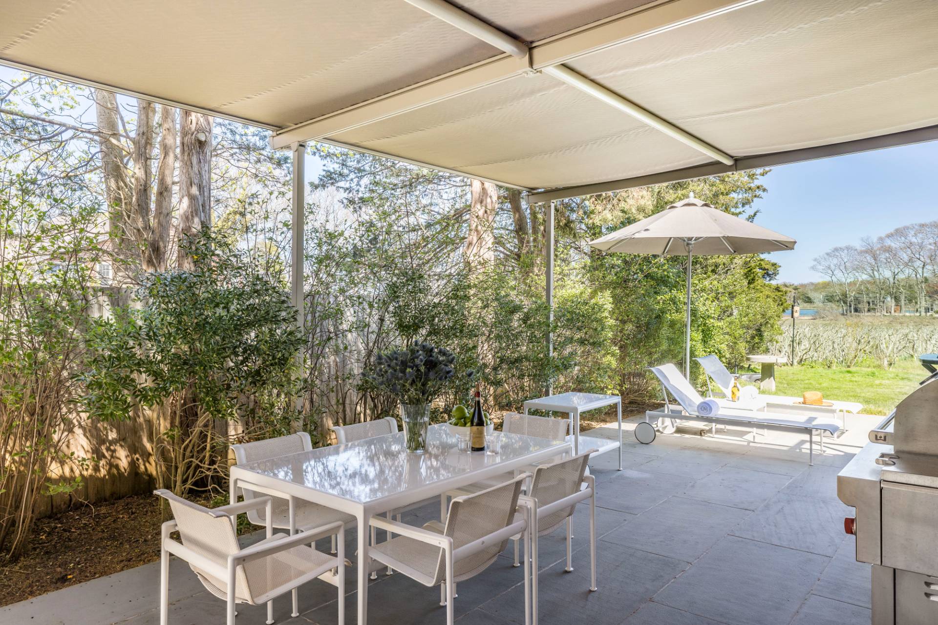 1084 Springs Fireplace Road East Hampton, NY 11937 - Photo 29 of 33 a view of a patio with table and chairs under an umbrella