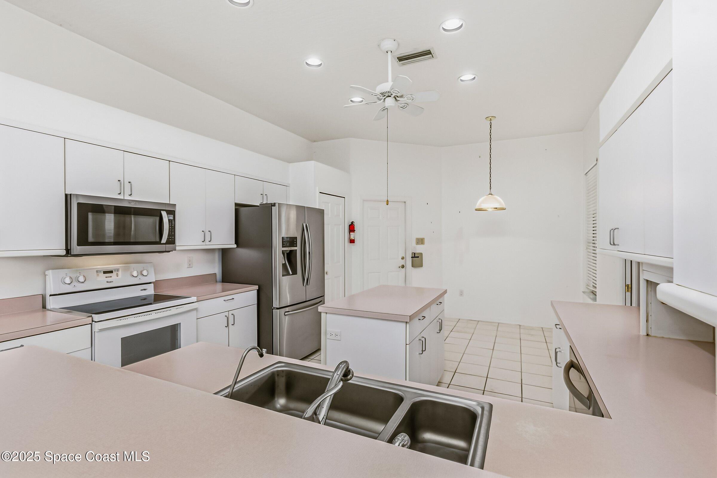 4048 Sand Ridge Drive Merritt Island, FL 32953 - Photo 18 of 70 a kitchen with stainless steel appliances kitchen island granite countertop a refrigerator a stove a microwave oven a sink with island and chairs