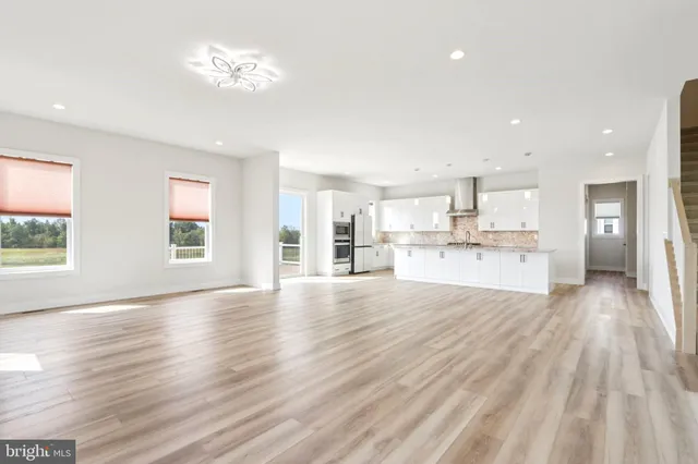 a view of a hallway with wooden floor and a bathroom