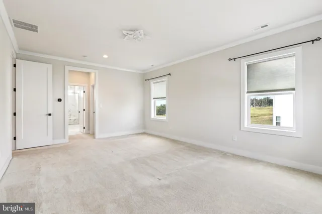 an empty room with wooden floor ceiling fan and windows