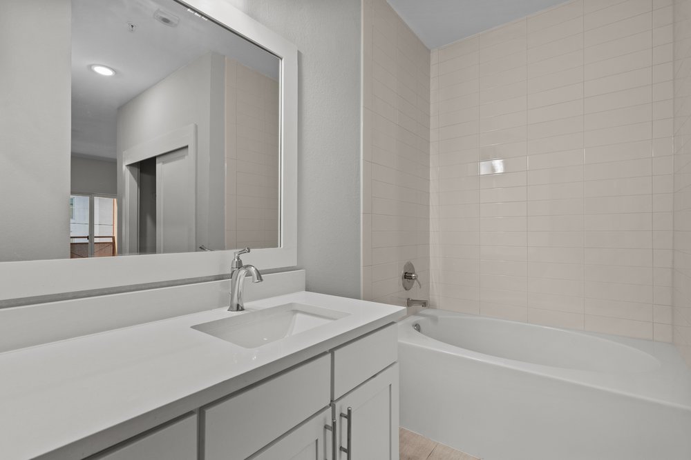 2827 Manor Road, Unit 2201 Austin, TX 78722 - Photo 27 of 40 Bathroom featuring a white vanity with an integrated sink, polished chrome faucet, and a large framed mirror