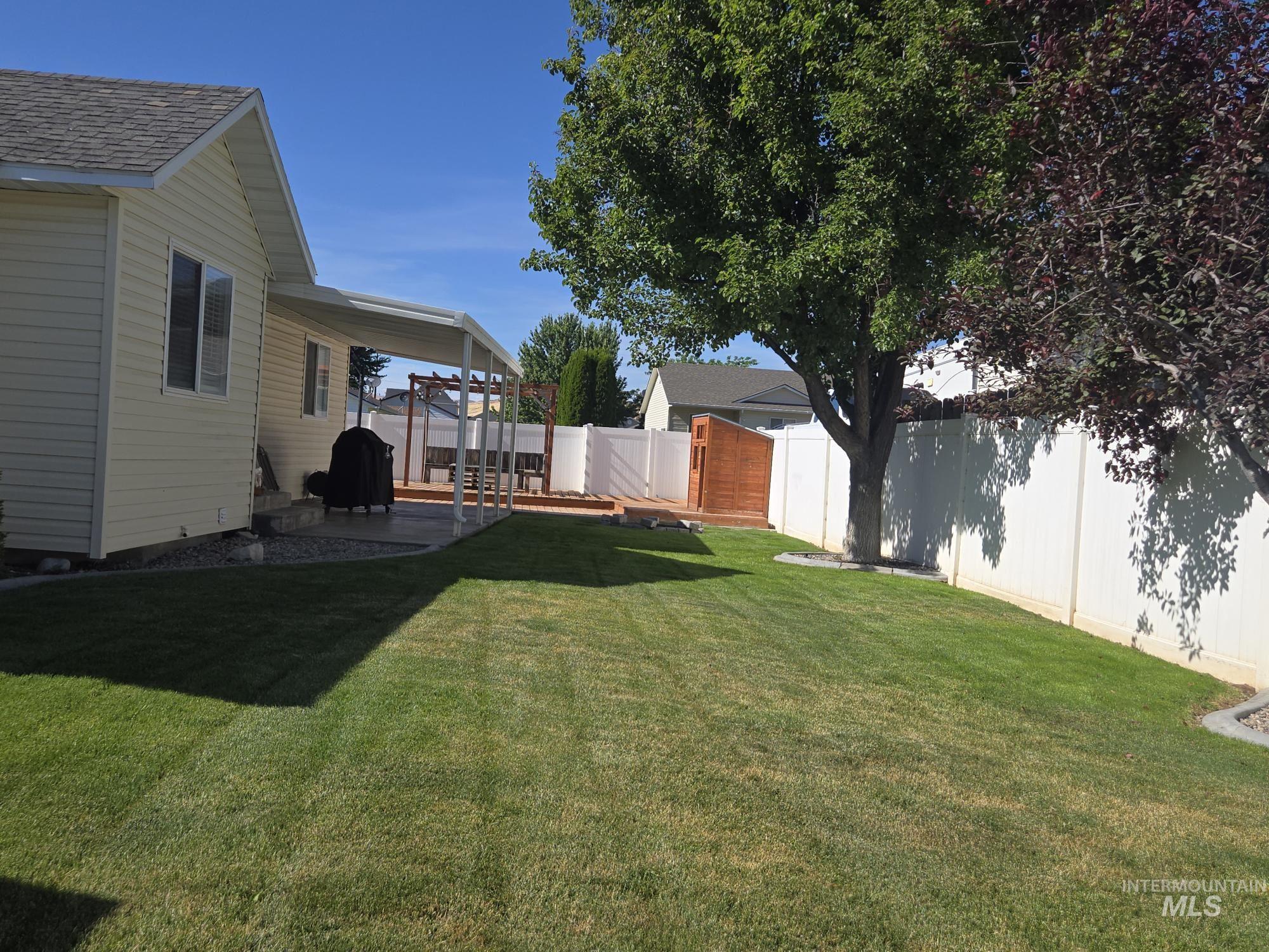 2480 West 9th Street Weiser, ID 83672 - Photo 3 of 17 Expansive backyard featuring a manicured lawn, white privacy fencing, and mature trees