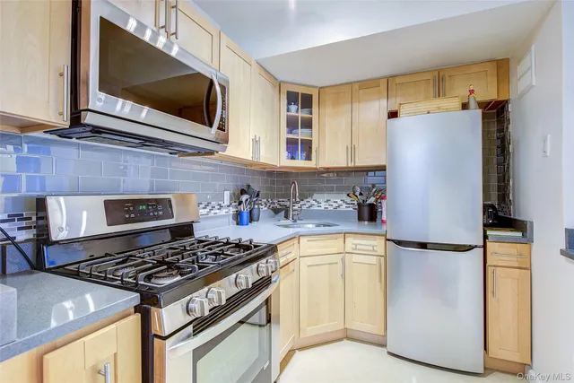 a kitchen with stainless steel appliances granite countertop a refrigerator a stove and a sink with wooden floor