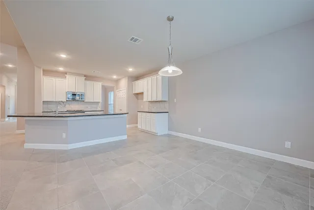 a large kitchen with kitchen island a stove a sink a refrigerator and white cabinets
