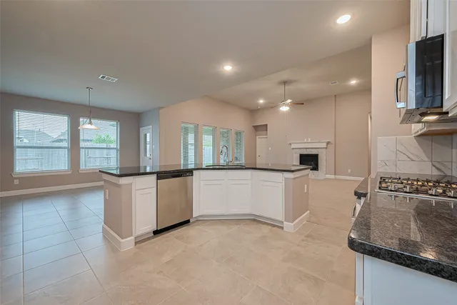 a kitchen with granite countertop white cabinets and stainless steel appliances