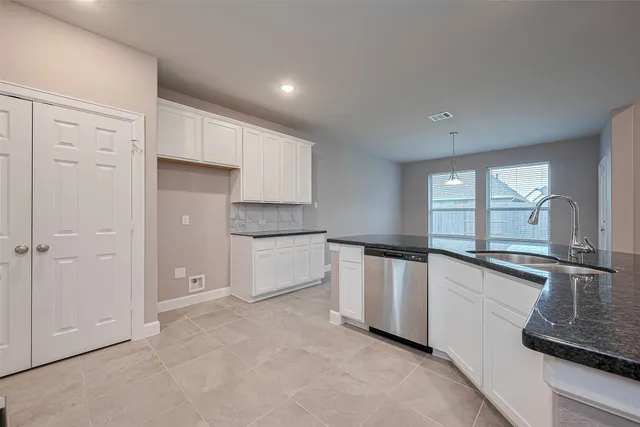 a kitchen with granite countertop white cabinets and stainless steel appliances