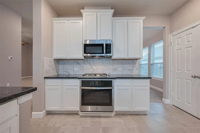 an empty room with windows and chandelier fan