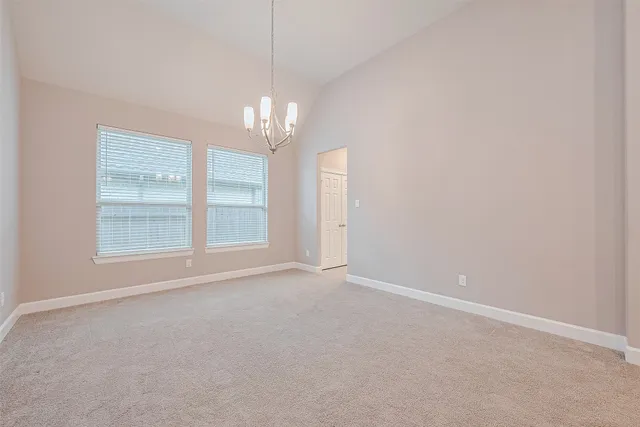 an empty room with a chandelier fan and windows
