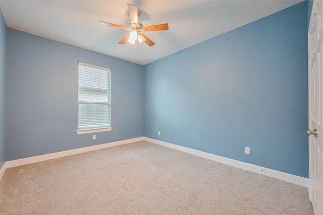 an empty room with chandelier fan and windows