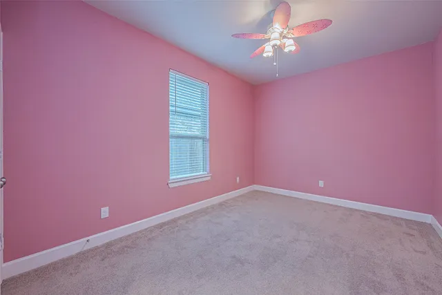 an empty room with chandelier fan and windows