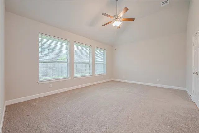 an empty room with a chandelier fan and windows