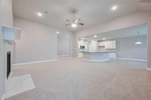 a view of an empty room and a kitchen view