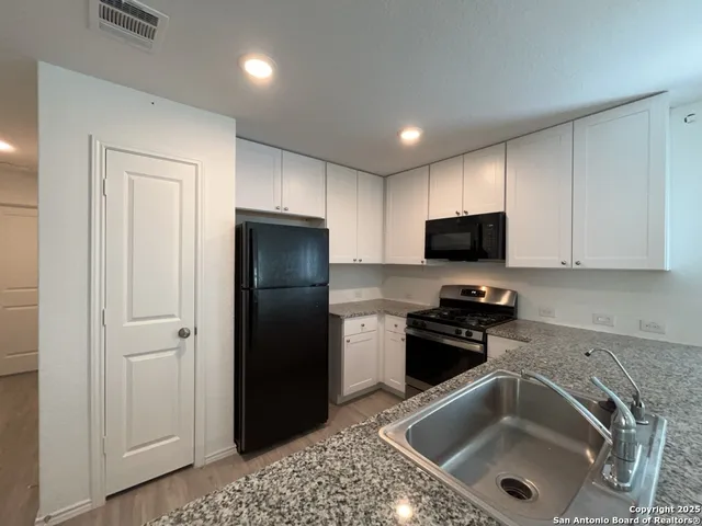 a kitchen with a sink a refrigerator and cabinets