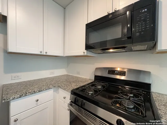 a kitchen with stainless steel appliances granite countertop white cabinets and black stove top oven with granite countertops