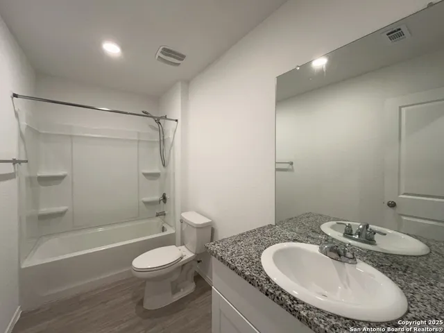 a bathroom with a granite countertop sink toilet a shower and a mirror