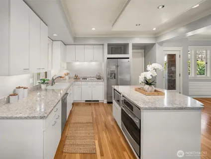 a kitchen with granite countertop a sink a counter top space stainless steel appliances and cabinets