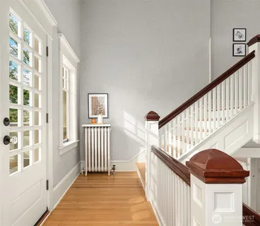 a view of staircase with lots of frames on wall and wooden floor