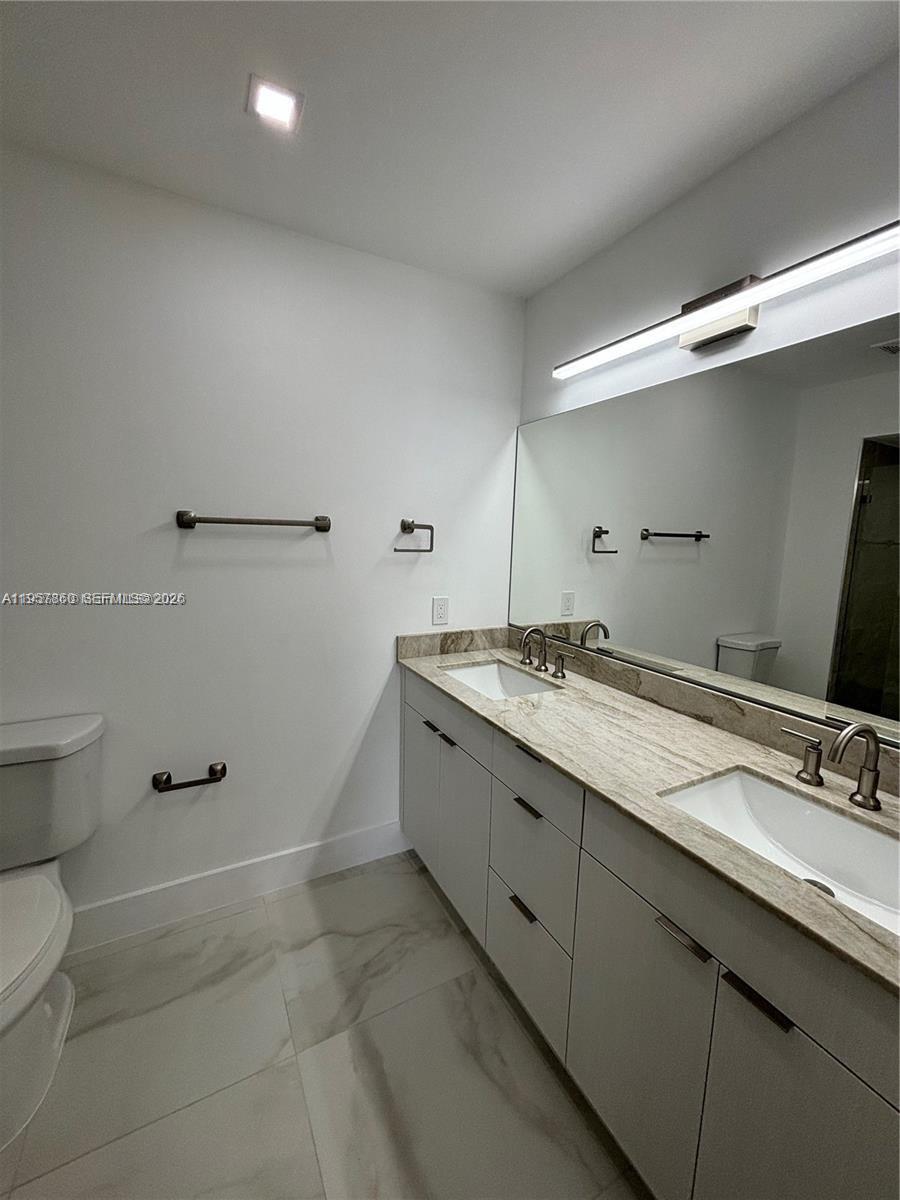 12637 Southwest 54th Street Miramar, FL 33027 - Photo 7 of 16 a bathroom with a granite countertop sink a toilet and a mirror