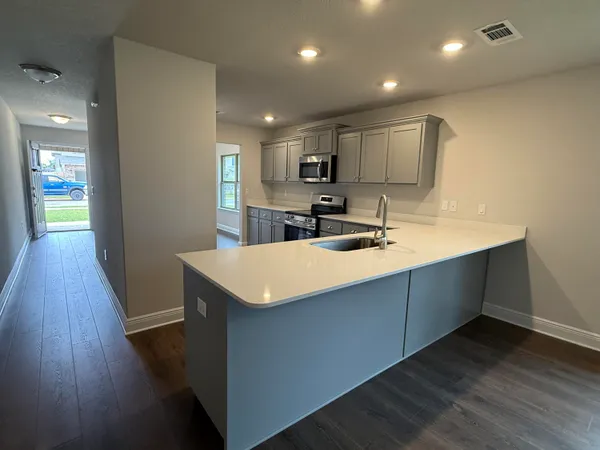 a kitchen with kitchen island a sink wooden floor and a refrigerator