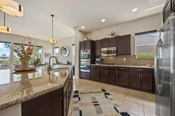 a kitchen with stainless steel appliances granite countertop a sink a stove and a wooden floors