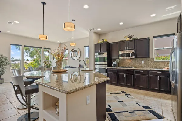 a kitchen with kitchen island stainless steel appliances a stove a sink a oven a clock and a chandelier