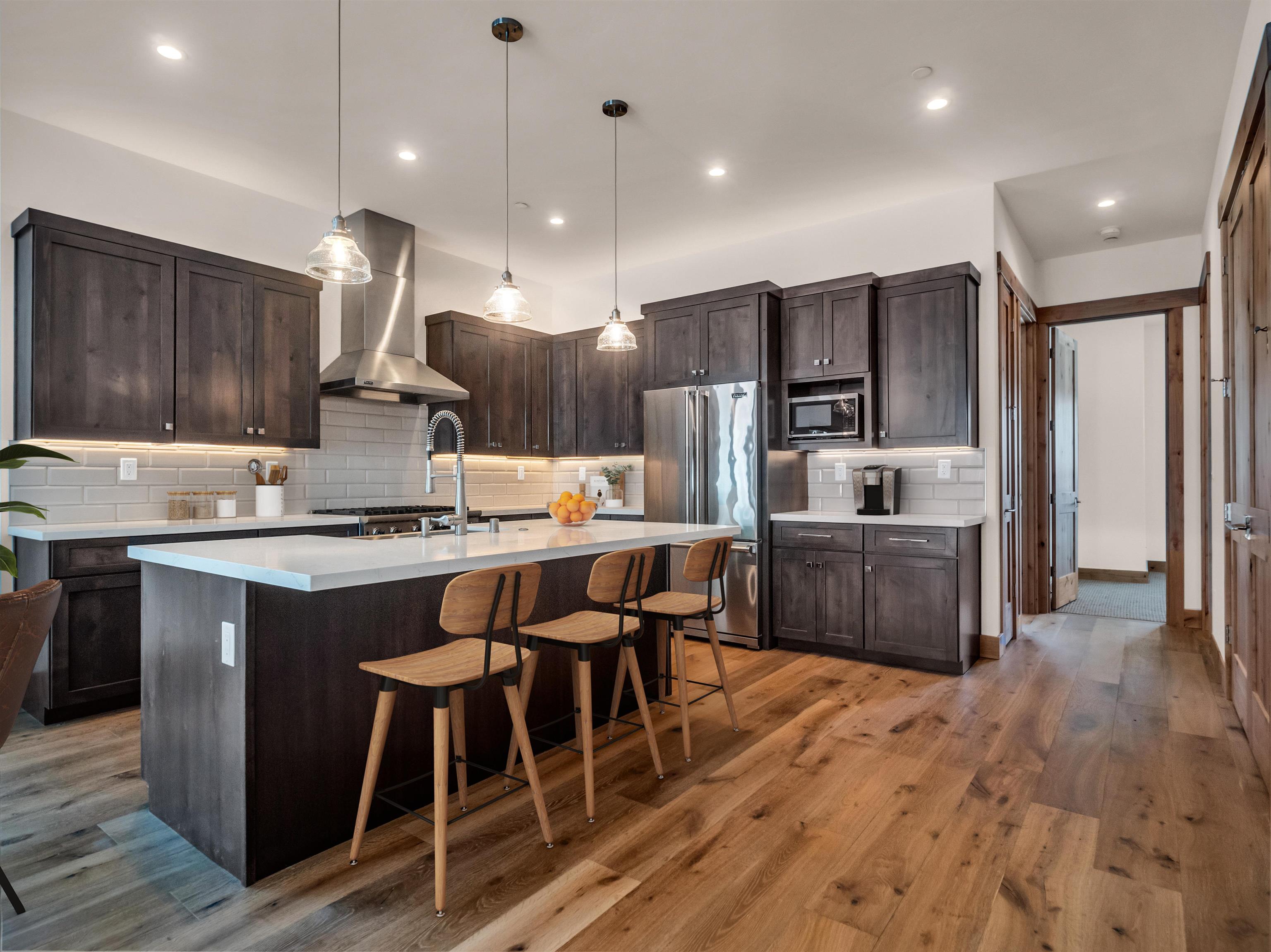 11643 McClintock Loop, Unit 3 Truckee, CA 96161 - Photo 3 of 21 a kitchen with stainless steel appliances kitchen island granite countertop a refrigerator a stove a sink dishwasher a dining table and chairs with wooden floor