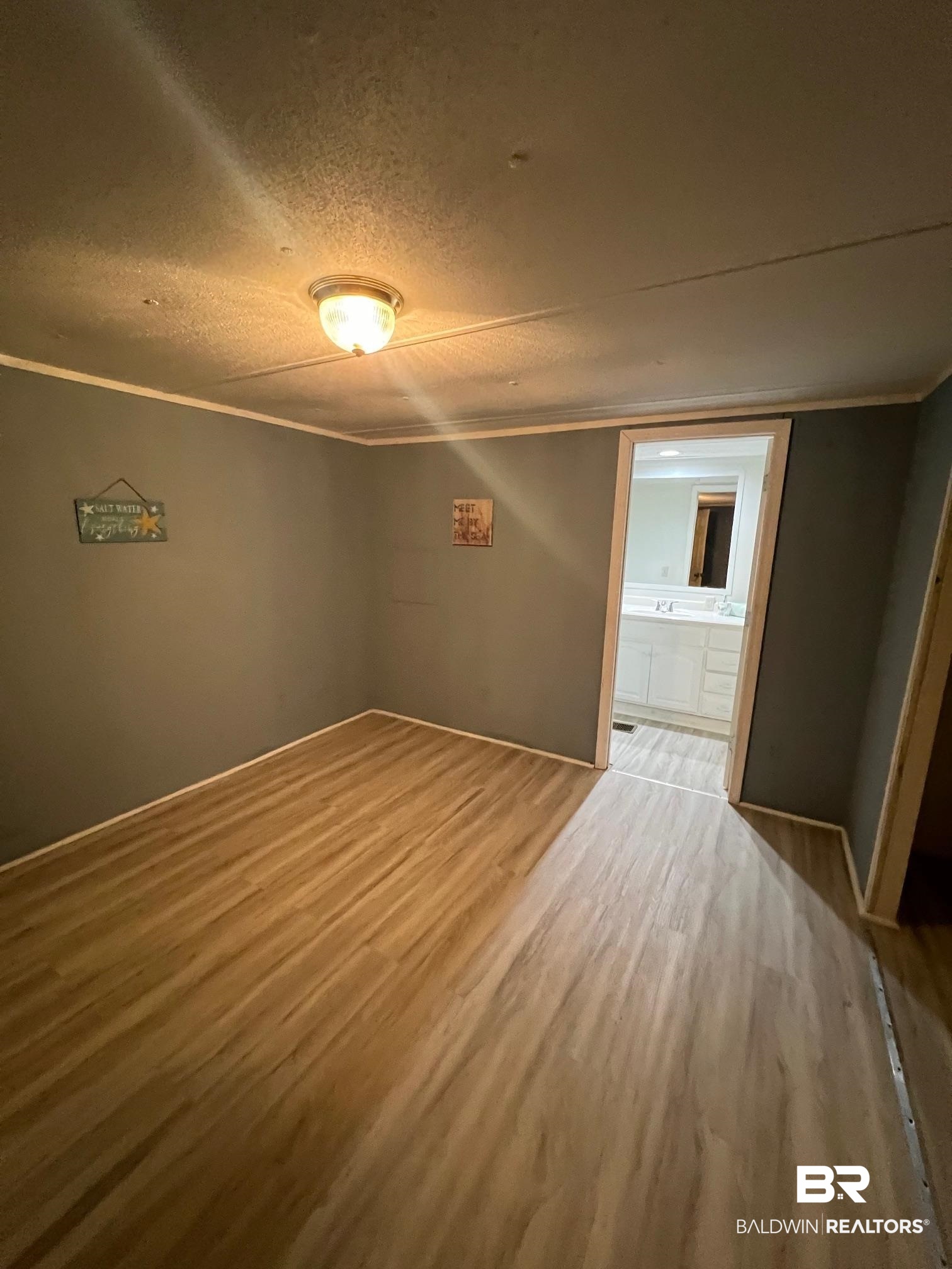 24994 Pompano Drive Elberta, AL 36530 - Photo 6 of 14 Empty room with wood finished floors, a textured ceiling, and ornamental molding