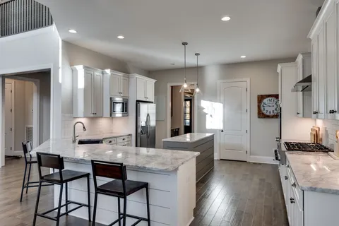 a large kitchen with granite countertop a large counter top appliances and cabinets