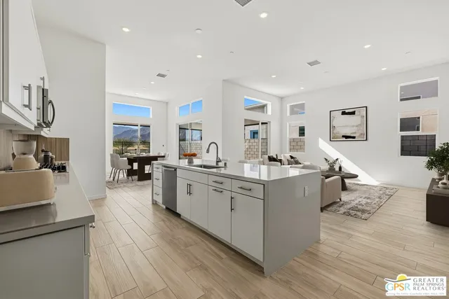 a large white kitchen with lots of counter space a sink and a refrigerator