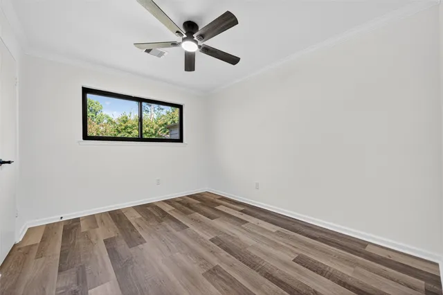 an empty room with wooden floor and ceiling fan