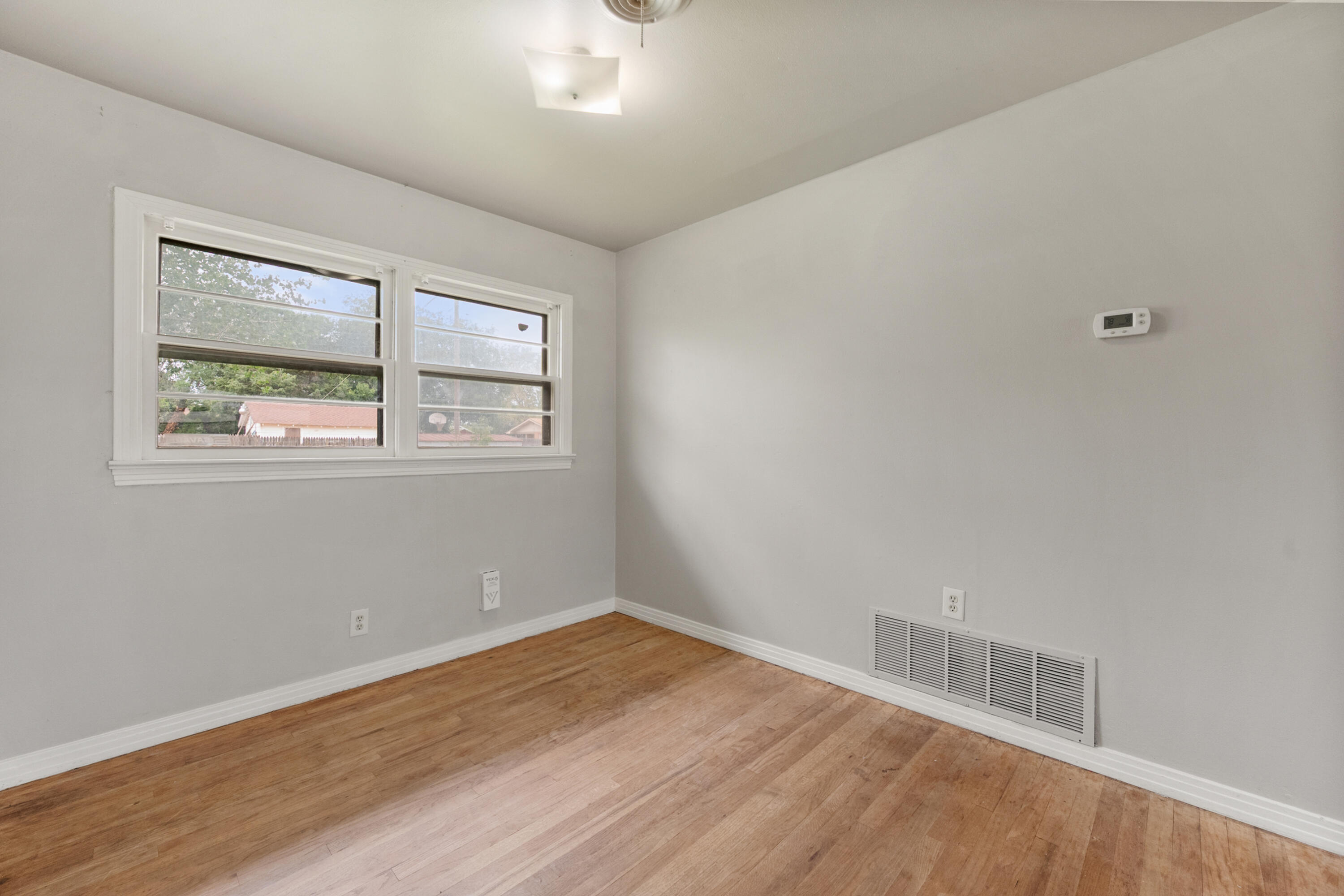 811 Zephyr Plainview, TX 79072 - Photo 8 of 25 an empty room with wooden floor and windows