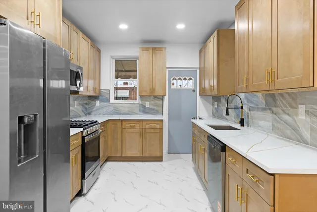 a kitchen with stainless steel appliances granite countertop a sink a stove and a refrigerator