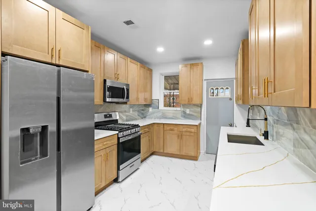 a kitchen with stainless steel appliances granite countertop a refrigerator a stove and a sink with wooden floor