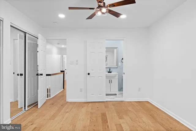 a view of empty room with wooden floor and ceiling fan