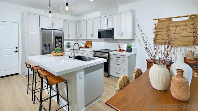 a kitchen with stainless steel appliances granite countertop a stove a refrigerator a sink a dining table and chairs with wooden floor