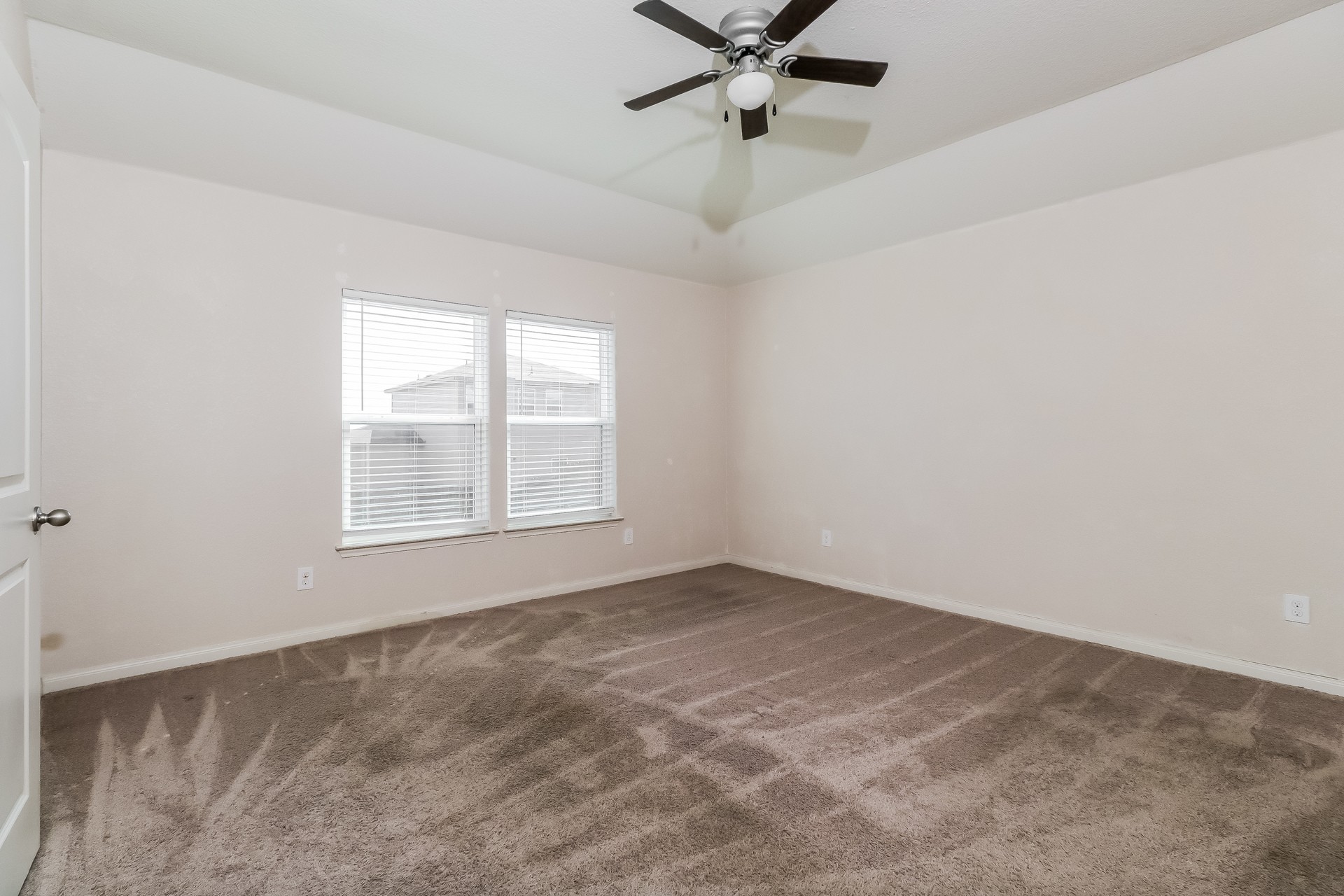 20017 Hubert R Humphrey Road Manor, TX 78653 - Photo 10 of 27 A spacious bedroom features plush carpeting and abundant natural light from dual windows, complemented by a contemporary ceiling fan.