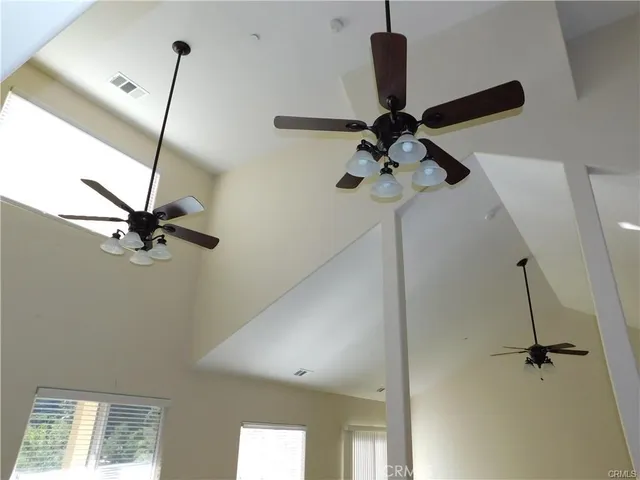 a room with a chandelier fan and a wooden floor